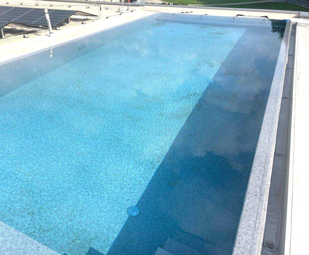 Großer Außenpool auf dem Dach mit klarem Wasser und umliegenden Fliesen.