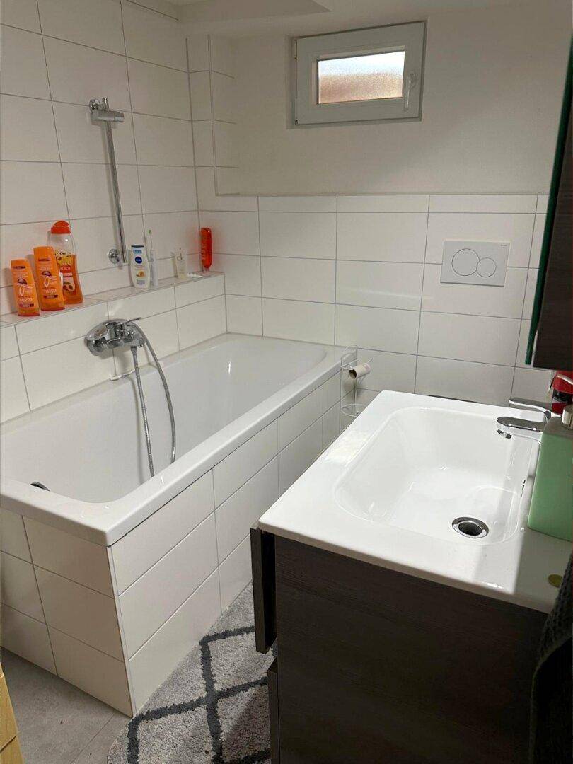 Helles Badezimmer mit Badewanne, Waschbecken und weiß gefliesten Wänden für eine saubere Optik.