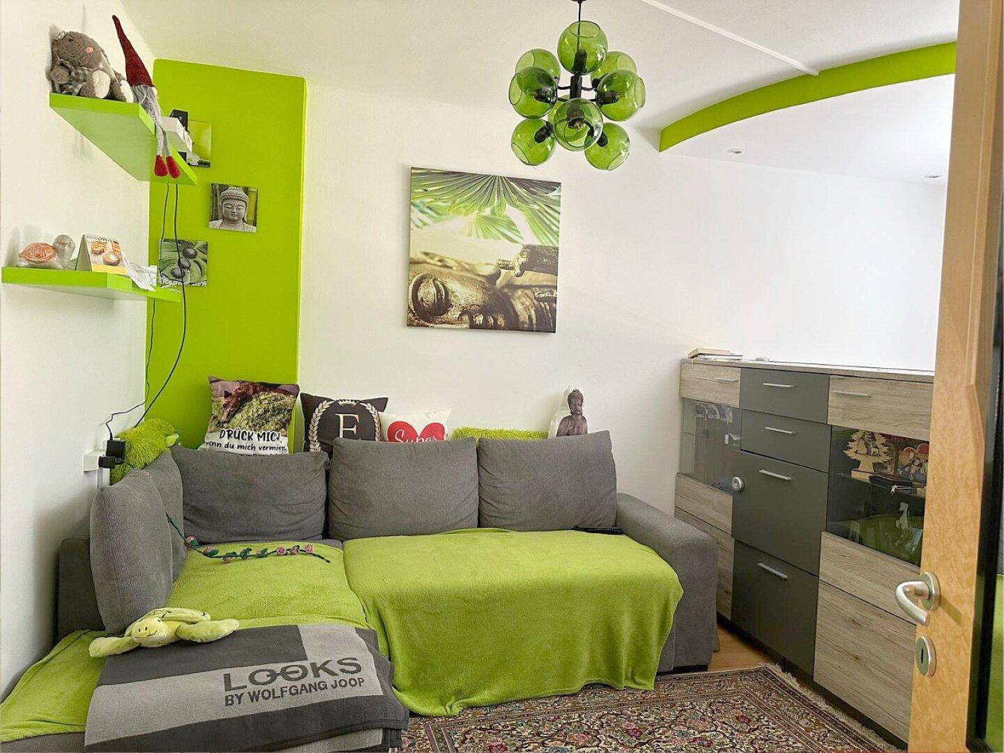Farbenfrohes Wohnzimmer mit Ecksofa, grünen Akzentwänden und Teppichboden für eine lebendige Atmosphäre.