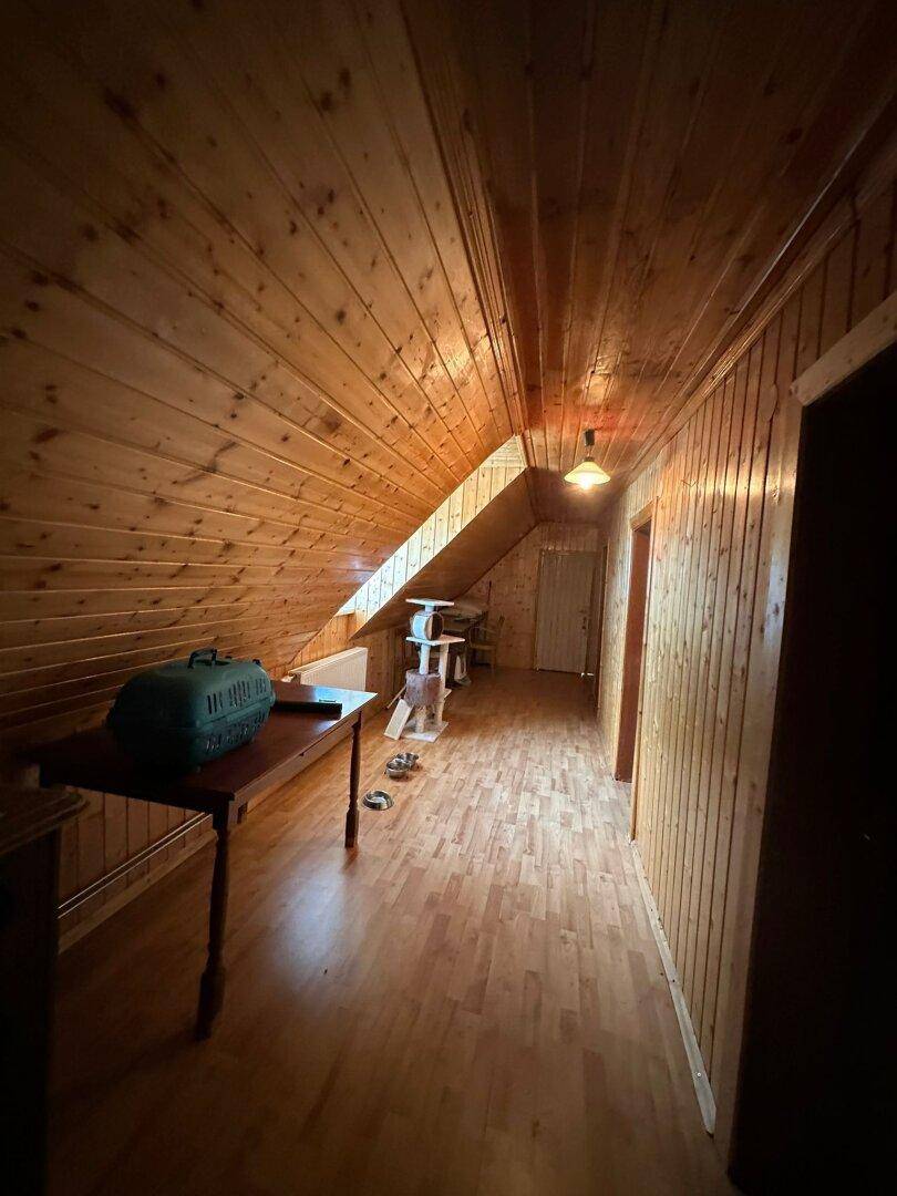 Schmaler Flur im Dachgeschoss mit Holzverkleidung an Wänden und Decke sowie Dachschräge.