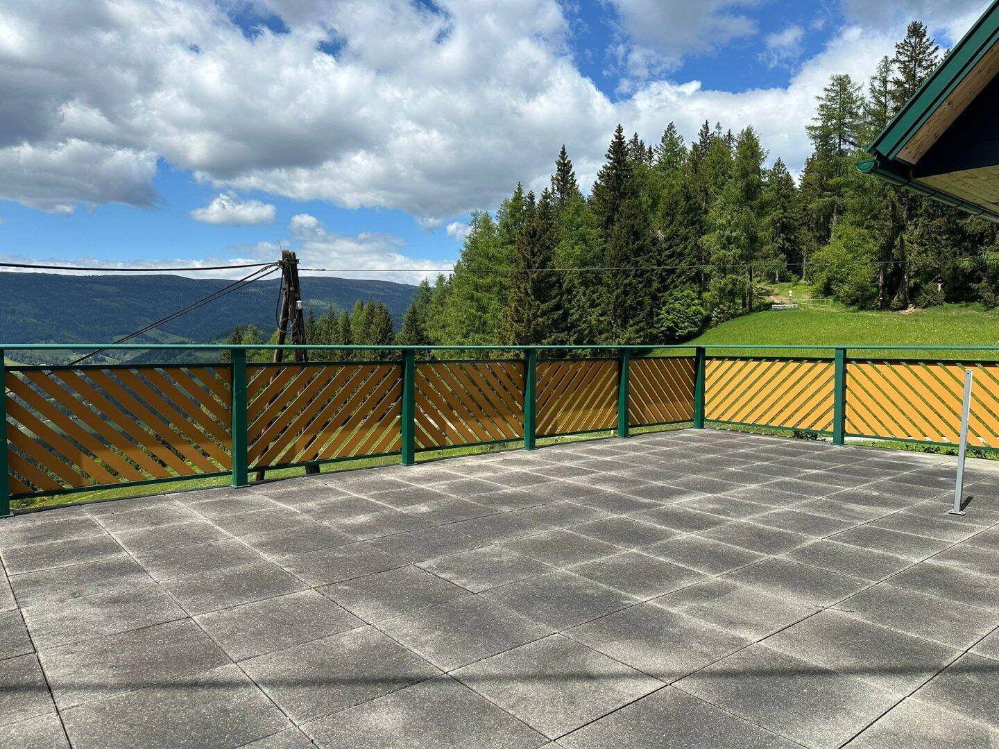 Geräumige Terrasse mit Holzzaun und atemberaubendem Panoramablick über die bewaldeten Hügel.