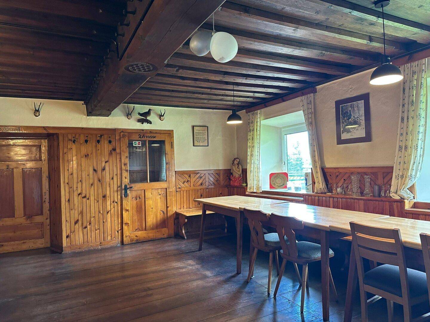 Gemütlicher traditioneller Essbereich mit Holztäfelung, Holzbalkendecke und rustikalen Möbeln.