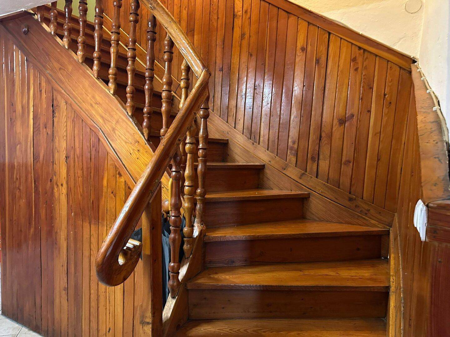Rustikale Holztreppe mit geschnitztem Geländer und Holztäfelung an den Wänden.