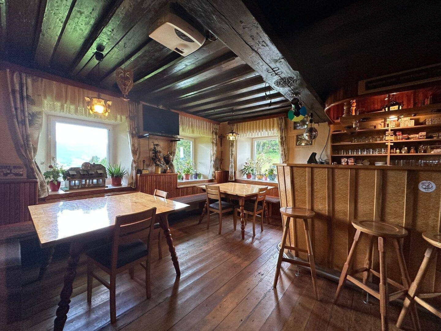 Rustikaler Gemeinschaftsraum mit Holzbalkendecke, Bar und mehreren Tischen mit Bergblick.