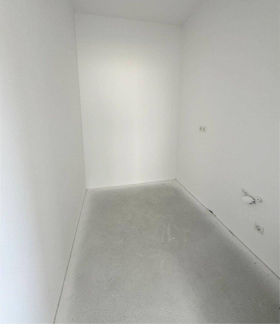 Kleiner, leerer Raum im Rohbau mit weißen Wänden und Betonboden, ideal als Abstellraum.