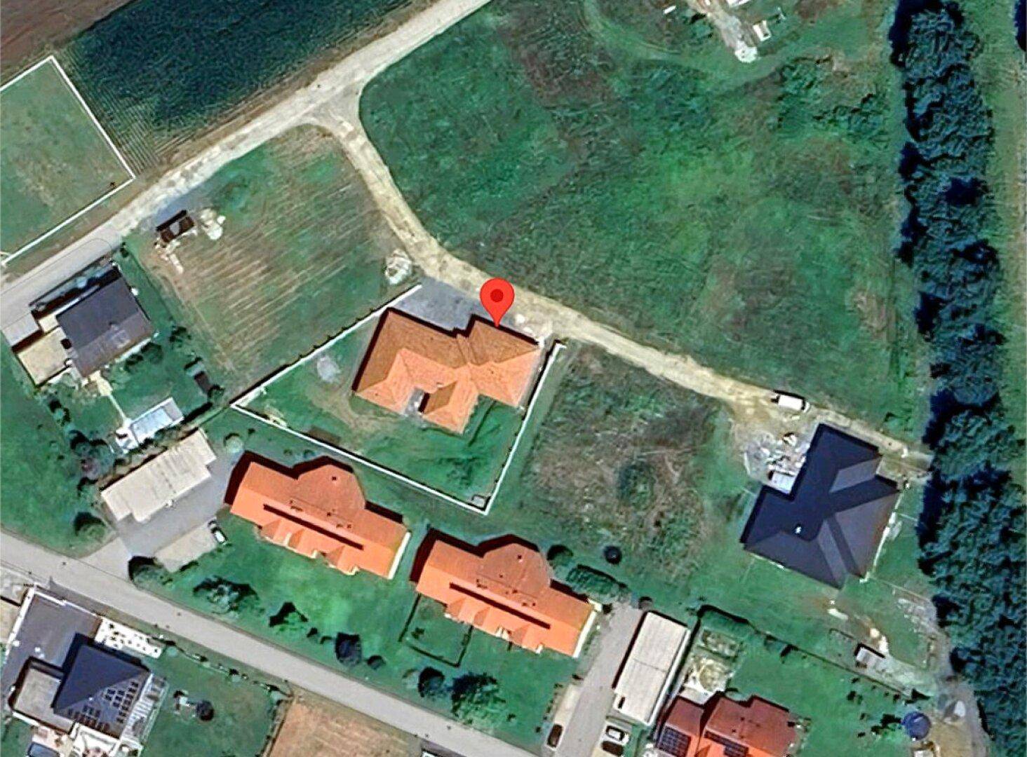 Satellitenansicht des Grundstücks mit Wohnhaus, rotem Dach und umliegender Grünfläche.