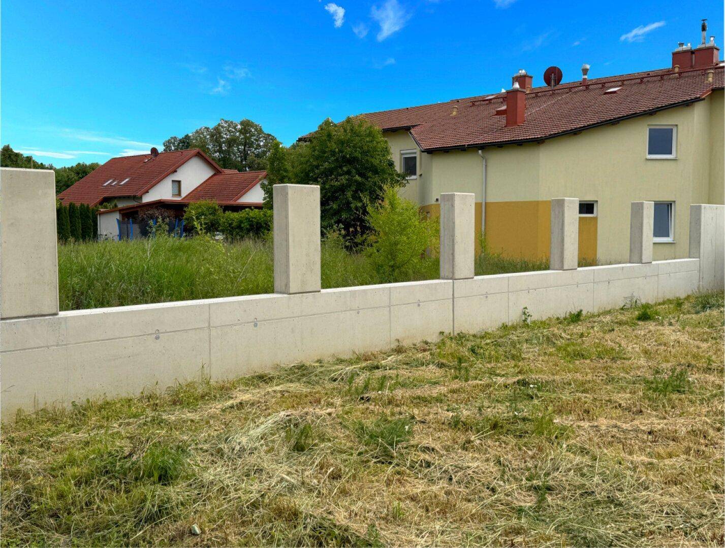 Neuer Zaun aus Betonpfeilern und -elementen trennt das Grundstück von den Nachbarhäusern.