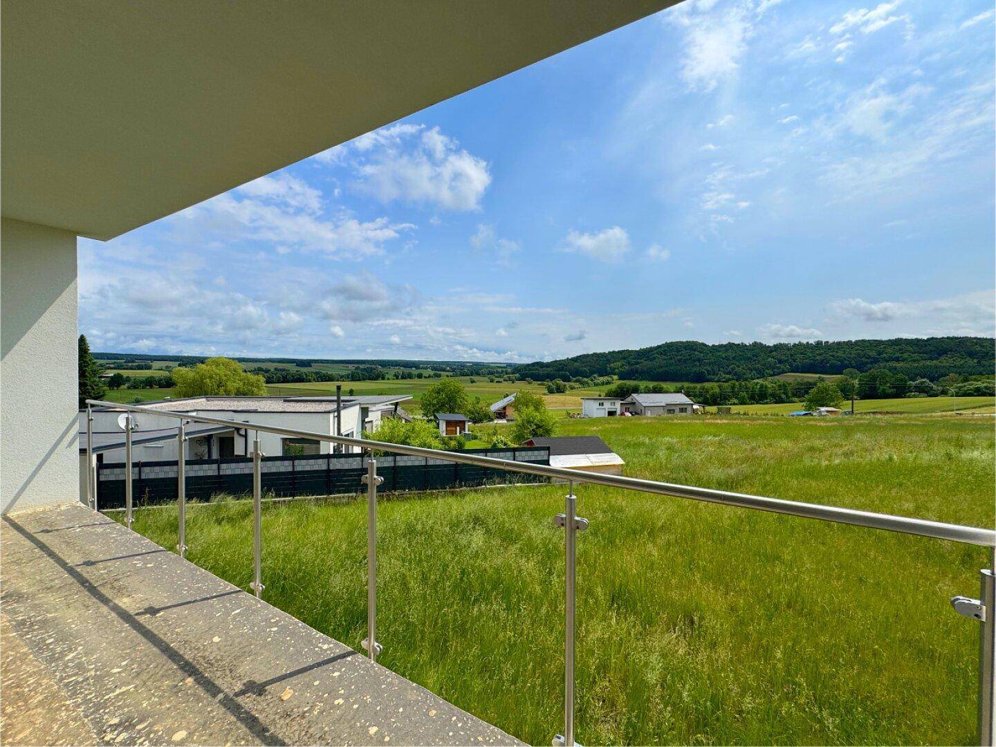 Weitläufiger Ausblick vom Balkon über die grüne Landschaft und umliegende Natur.