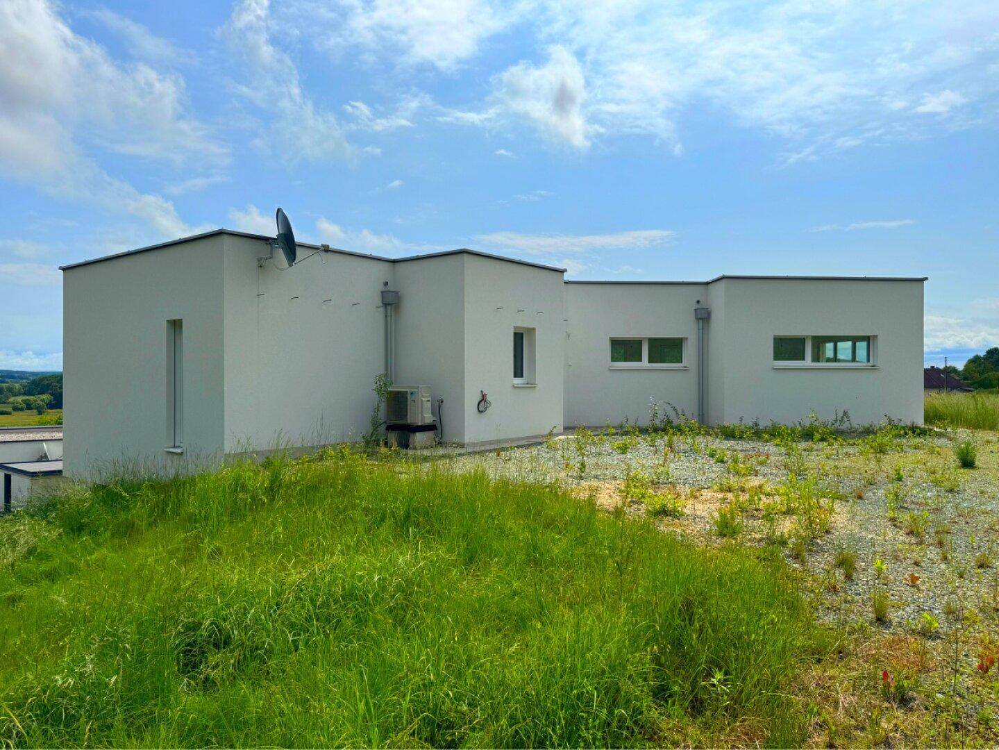 Rückansicht des modernen Hauses mit Flachdach und weitem Blick über die Landschaft.