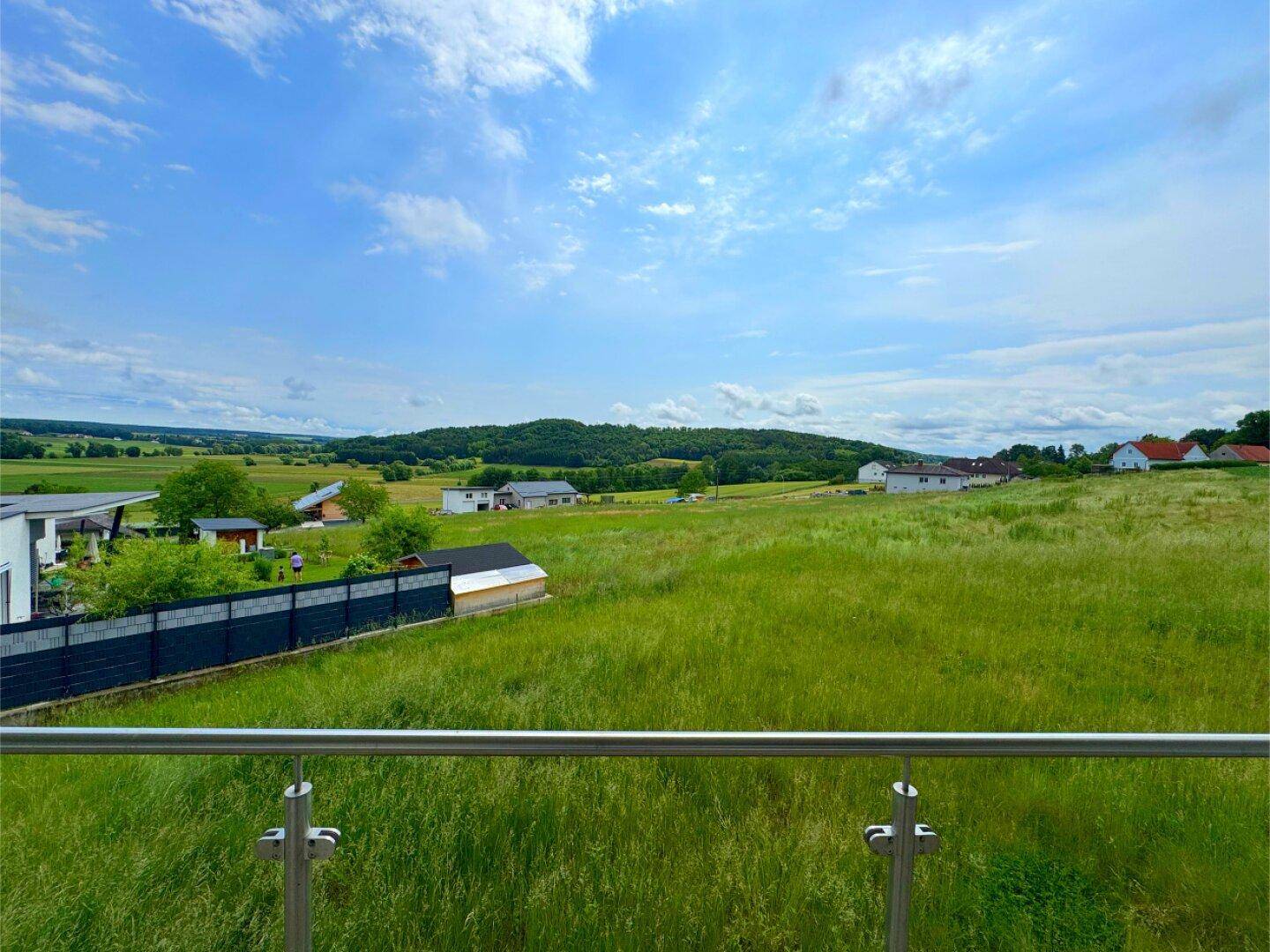 Panoramablick vom Balkon auf die idyllische grüne Landschaft unter blauem Himmel.