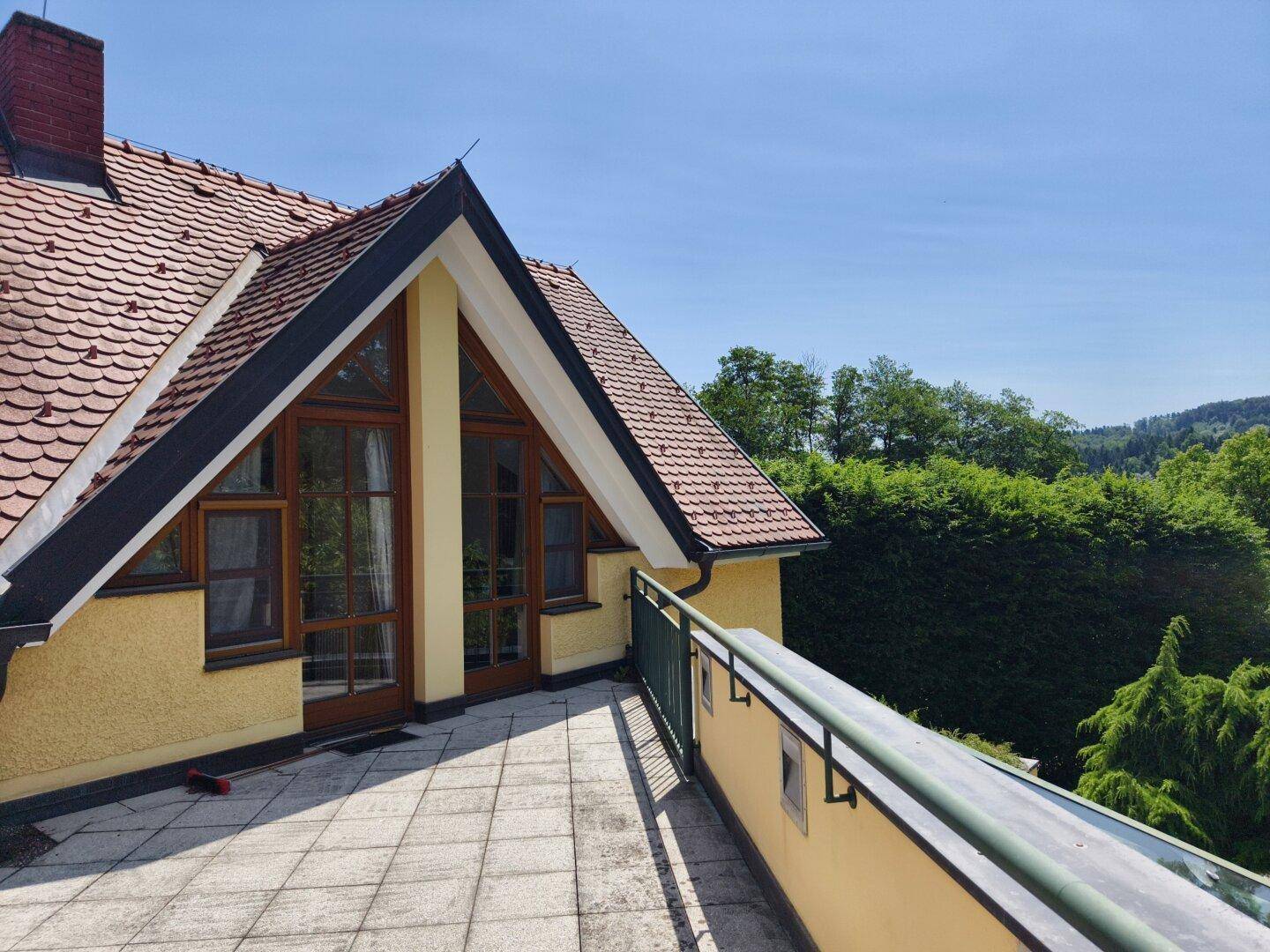 Geräumige Dachterrasse mit Fliesenboden und weitem Blick über die grüne Hügellandschaft.