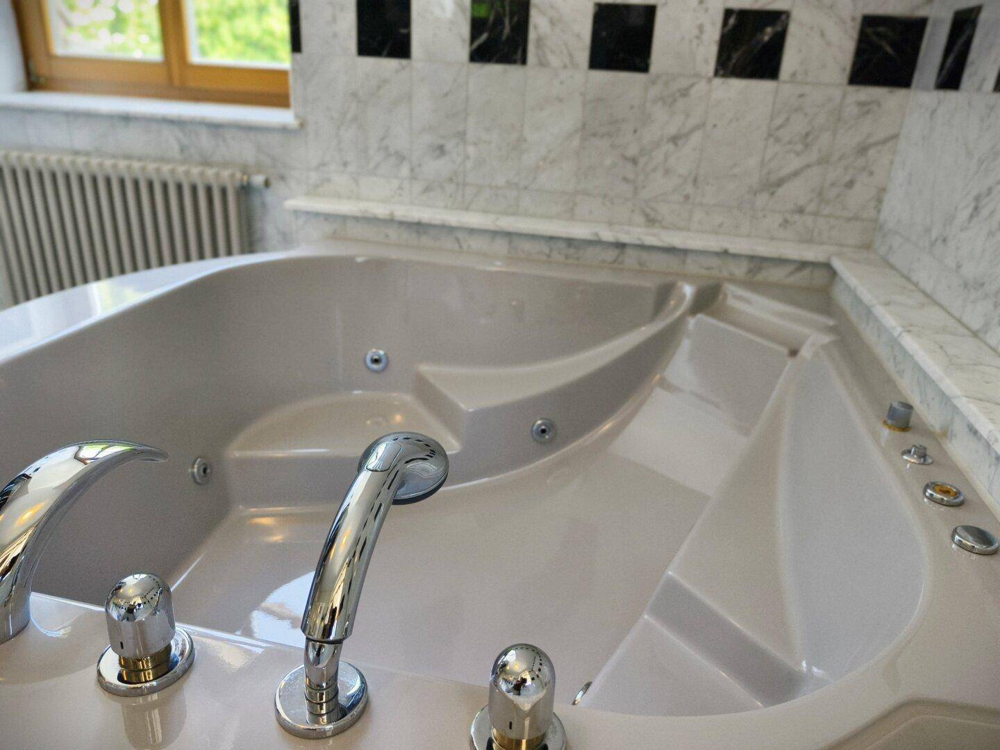 Nahaufnahme der Eckbadewanne mit Whirlpool-Funktion und modernen Armaturen.
