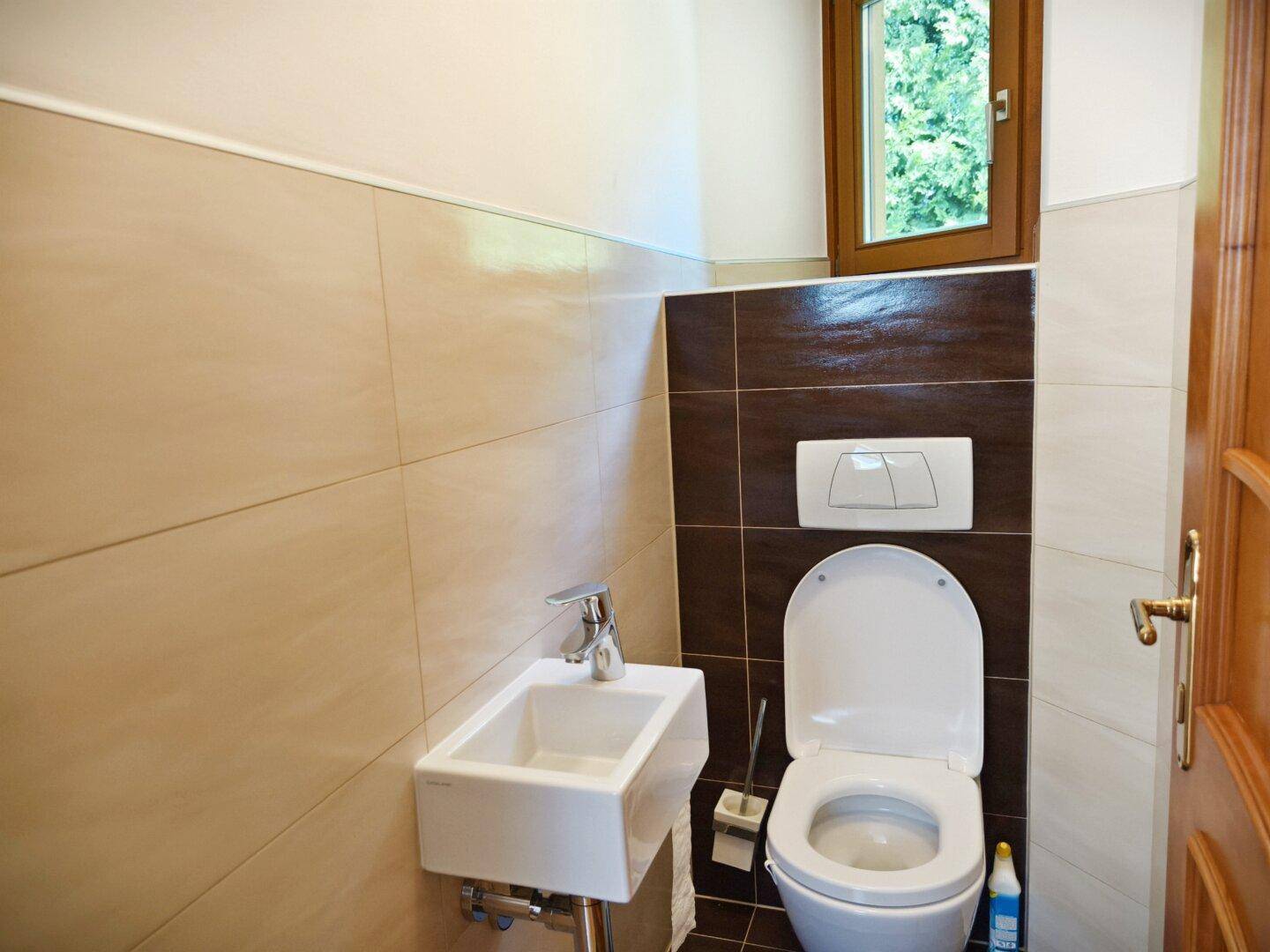 Kleines Gäste-WC mit Fenster, modern gefliest und mit wandhängendem WC.