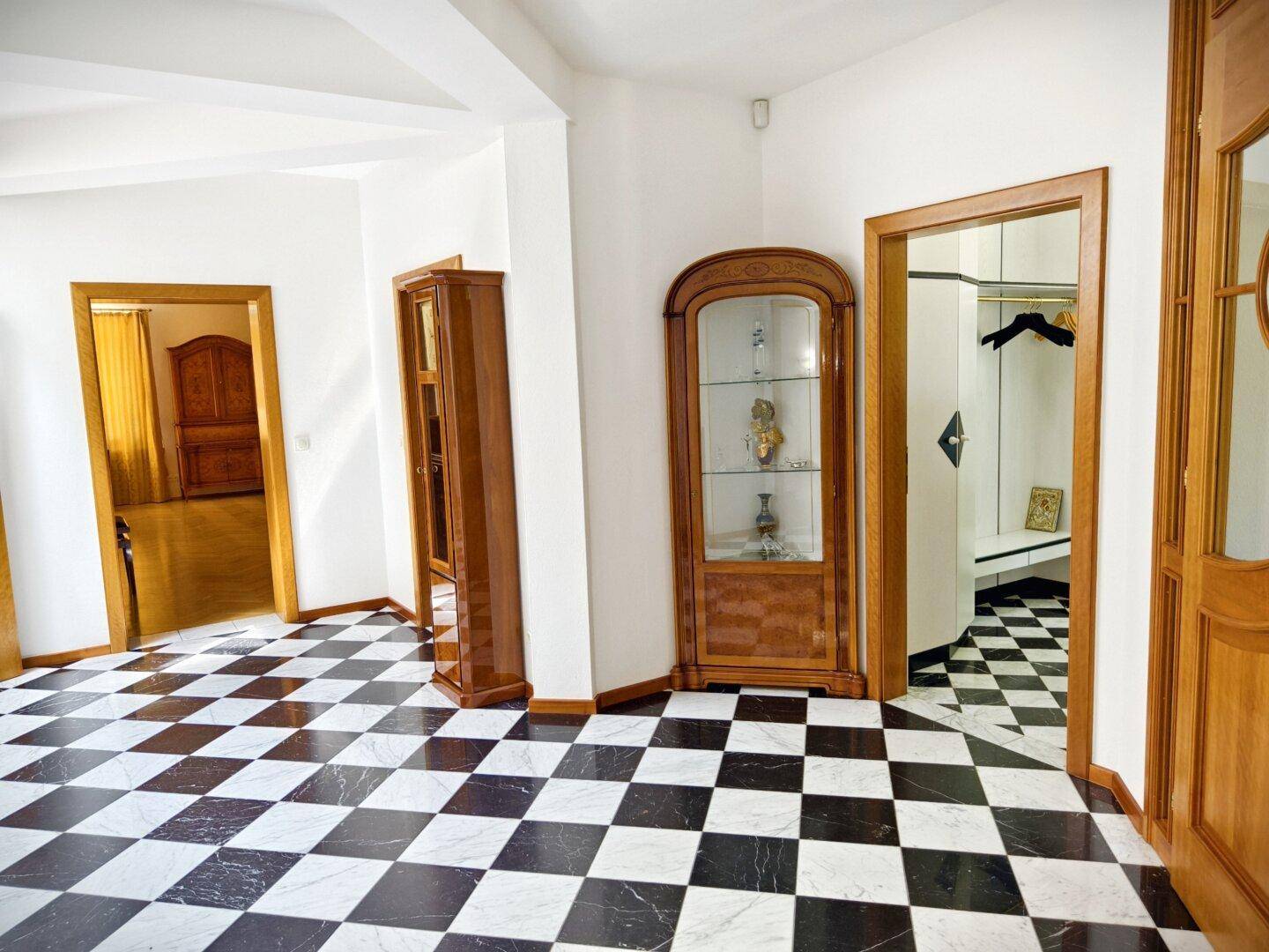 Geräumiger Flur mit schwarz-weiß kariertem Fliesenboden und eleganten Vitrinen.