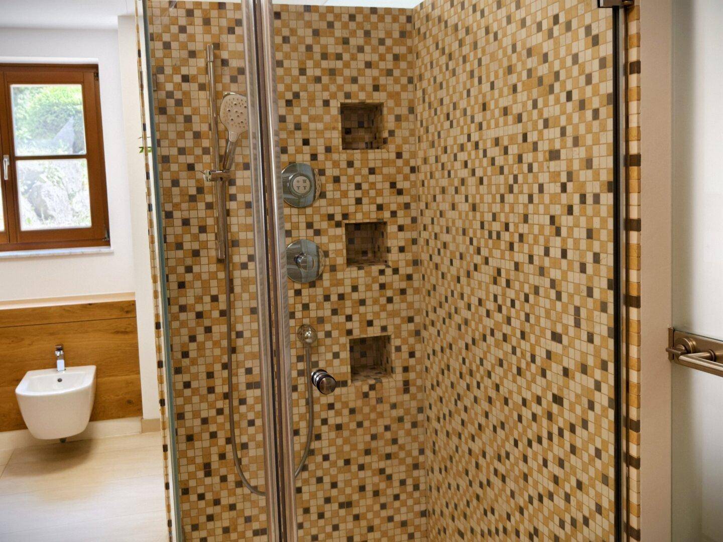 Geräumige Duschkabine mit Mosaikfliesen und mehreren Duschköpfen.