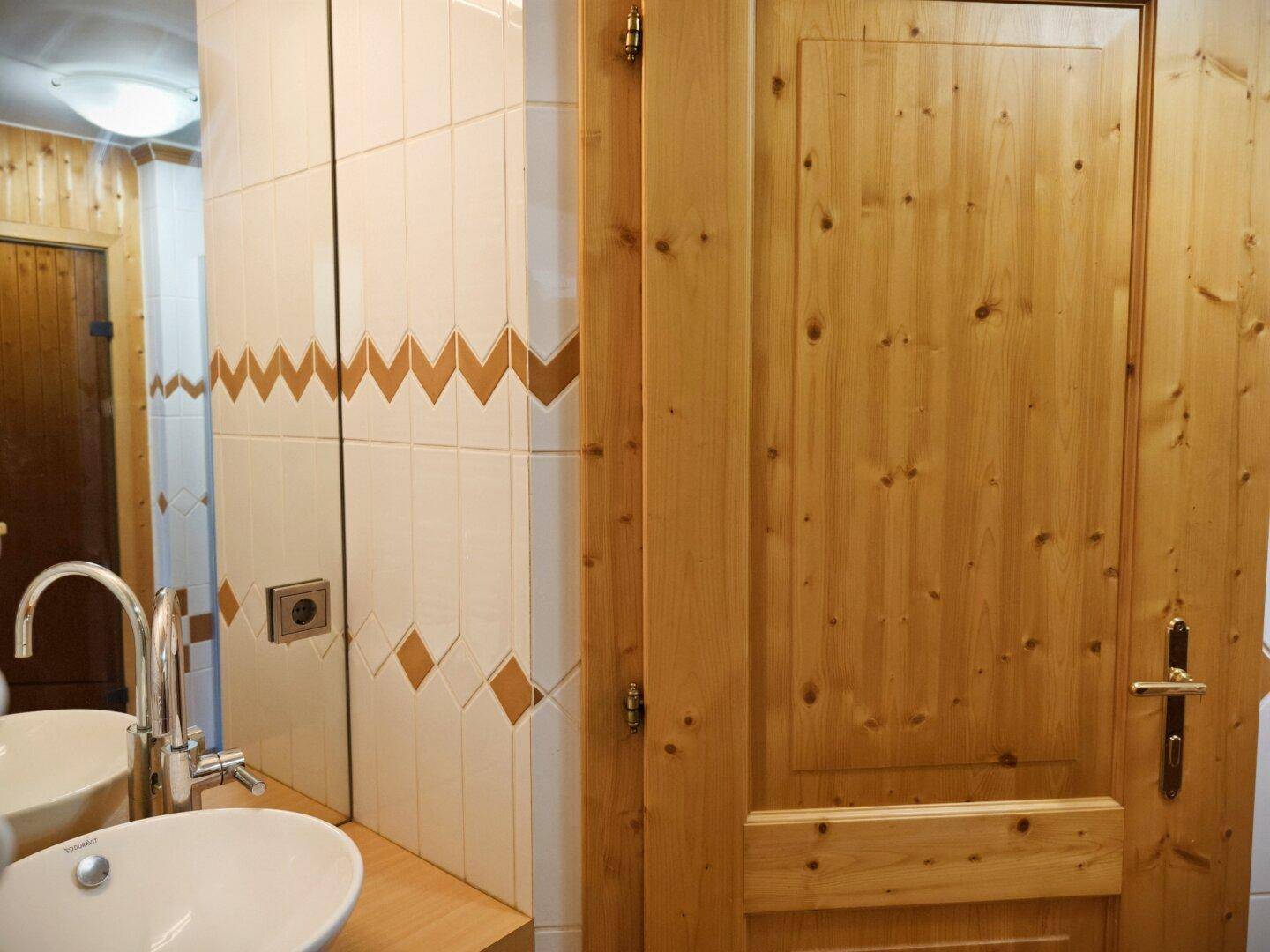 Rustikales Badezimmer mit Holzverkleidung, Waschbecken und Spiegel.