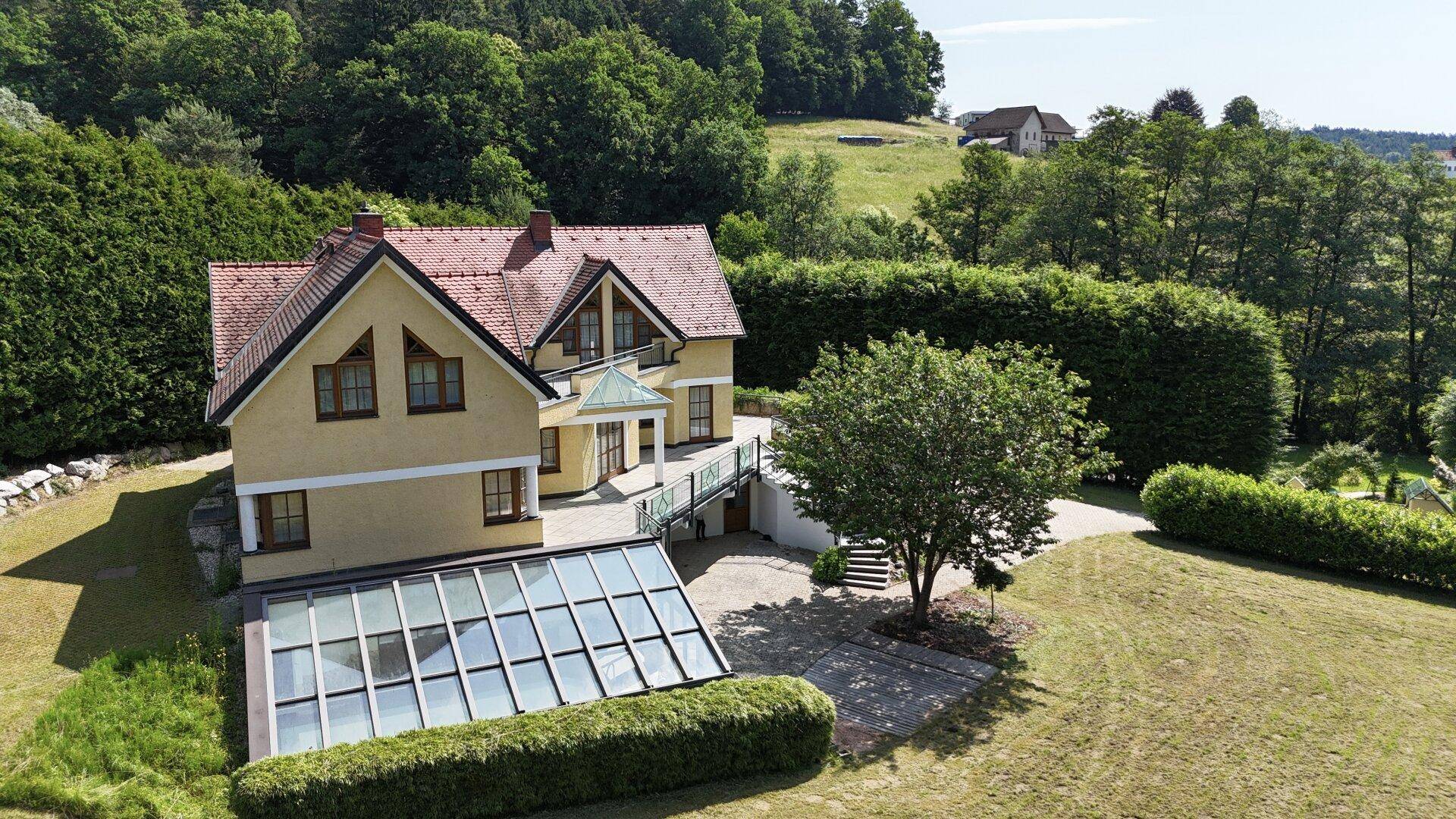 Großzügiges Haus mit gelber Fassade, rotem Dach und weitläufigem Gartenbereich.