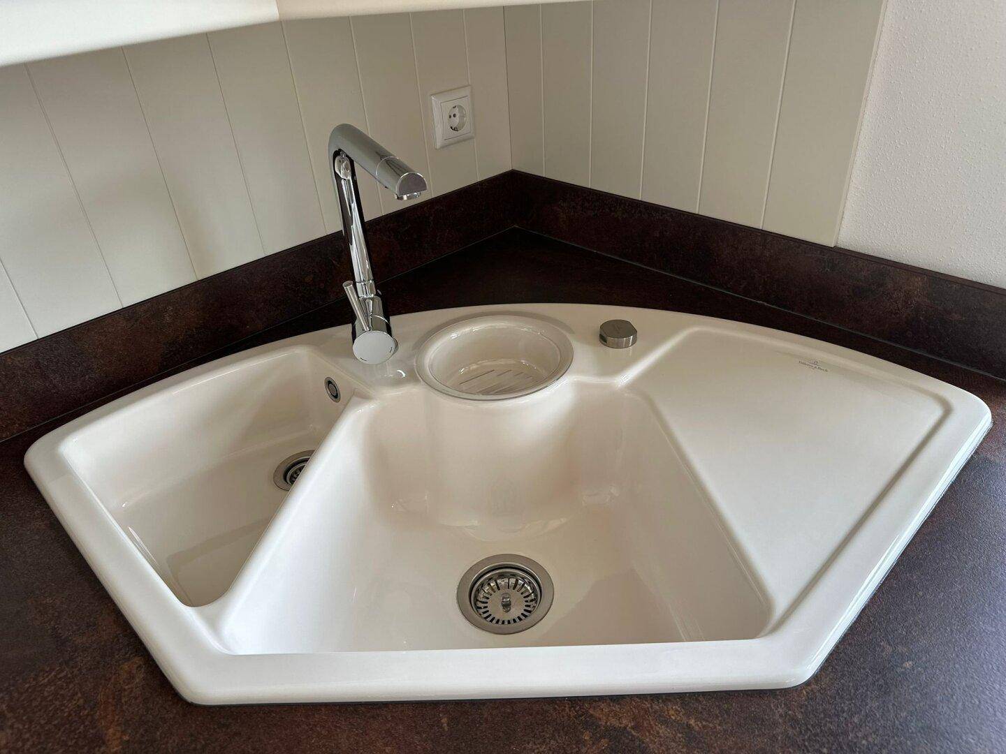 Eckspüle in der Küche mit zwei Becken, Abtropffläche und modernem Wasserhahn.