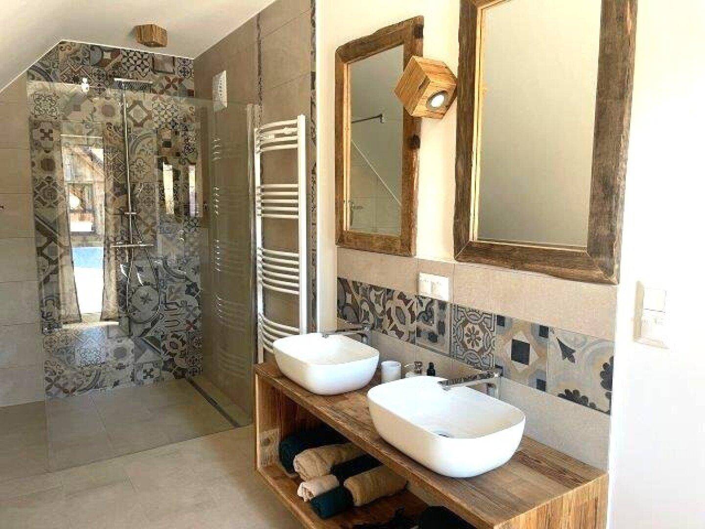 Geräumiges Badezimmer mit zwei Waschbecken, großer Dusche und gemusterten Fliesen im Bau.