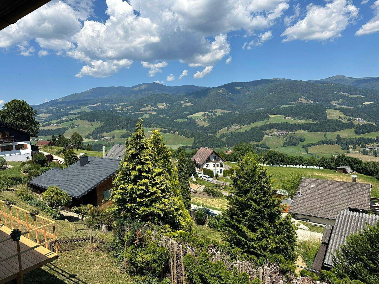 Überblick über die Liegenschaft und die Nachbarschaft, eingebettet in die grüne Berglandschaft unter blauem Himmel.