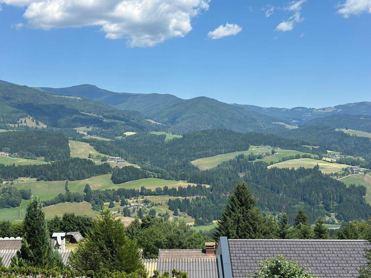 Malerischer Ausblick auf die unberührte Natur mit weiten grünen Tälern und imposanten Bergketten.