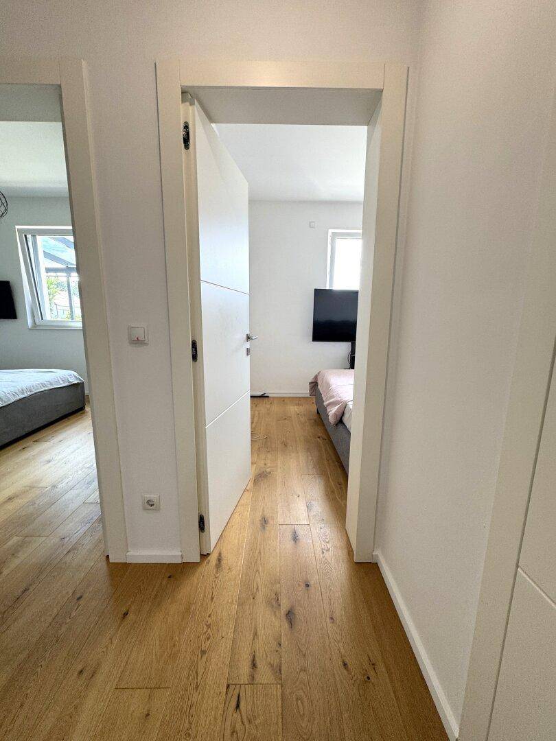 Heller Flur mit Holzparkettboden, der den Zugang zu den angrenzenden Schlafzimmern ermöglicht.
