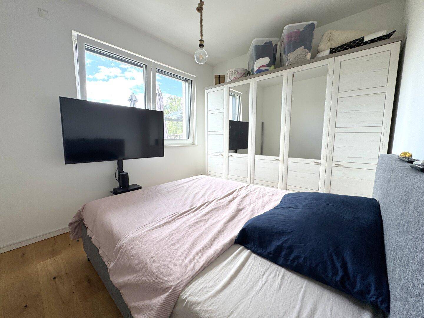 Gemütliches Schlafzimmer mit Doppelbett, großem Kleiderschrank und Fenster, das viel Tageslicht hereinlässt.