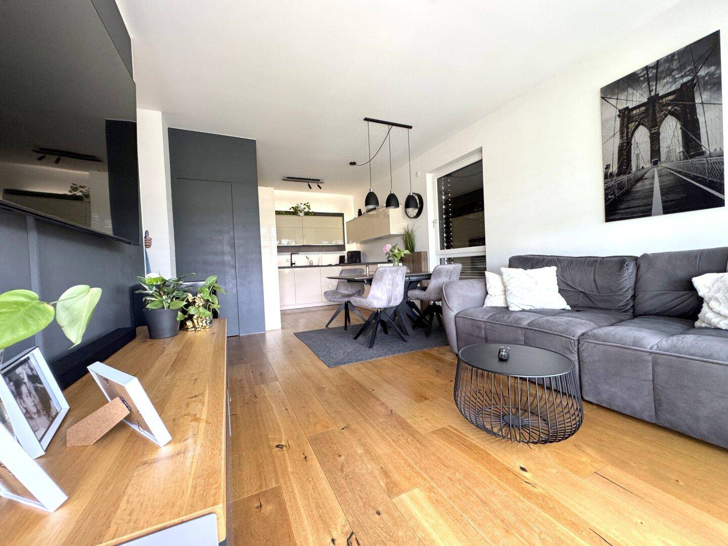 Offener Wohn- und Essbereich mit moderner Küche, Holzparkettboden und Zugang zur Terrasse.