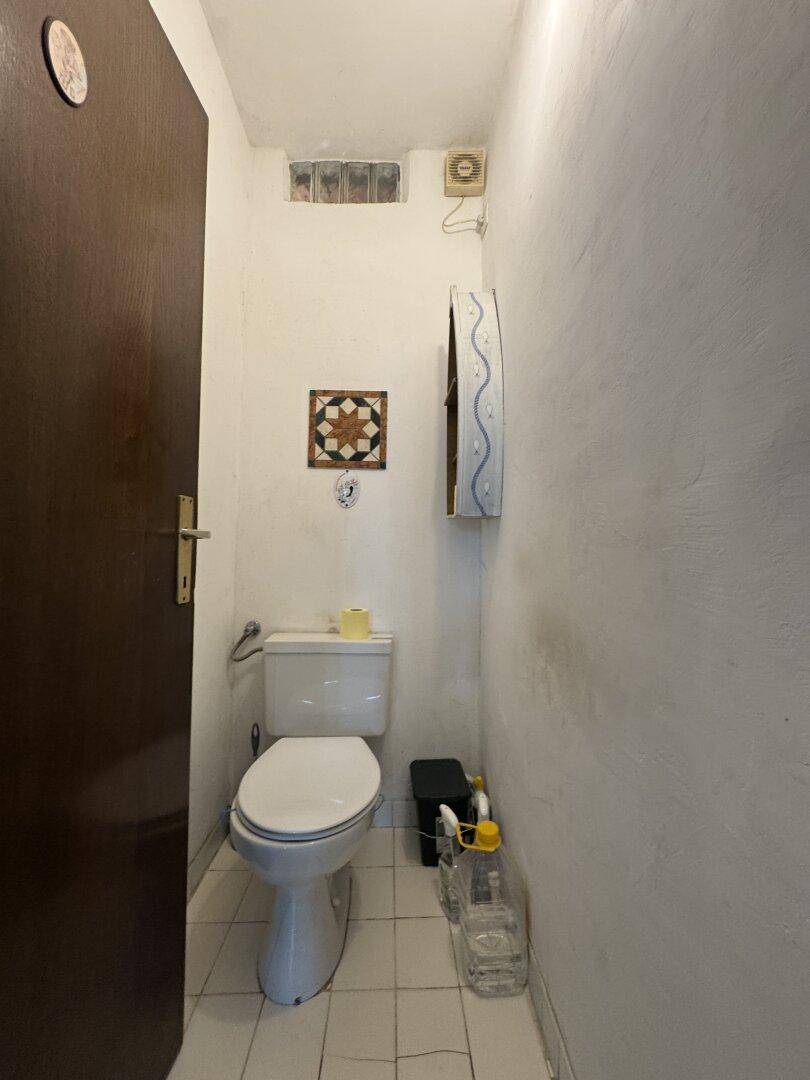 Kleines Gäste-WC mit weißer Toilette, Fliesenboden und einfacher Ausstattung.