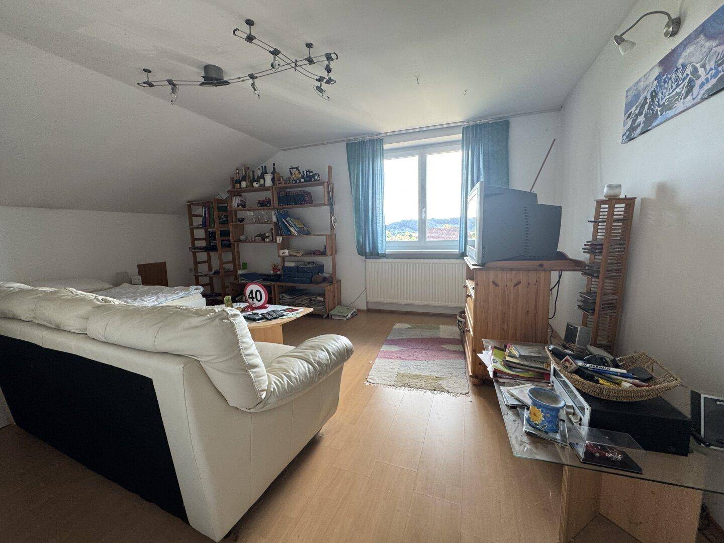 Gemütliches Wohnzimmer im Dachgeschoss mit Schrägdach, Sofa und Blick ins Grüne.