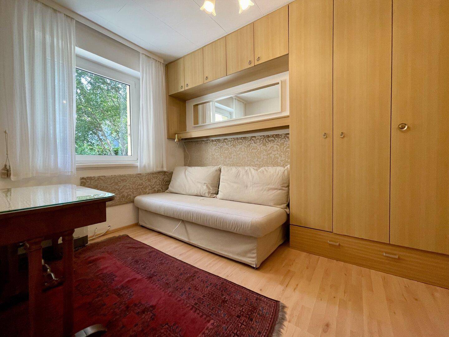 Schlafzimmer mit Einzelbett, Einbauschränken und Holzboden.
