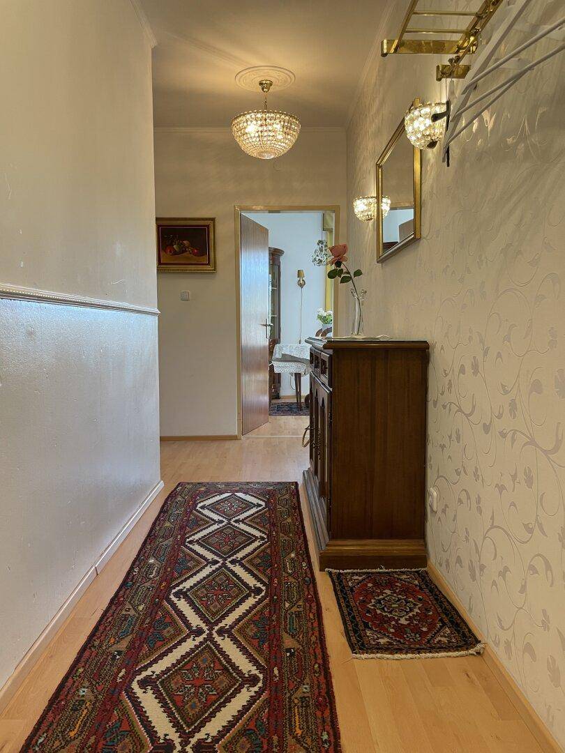Heller Flur mit Holzboden, Teppichläufer und Garderobe an der Wand.