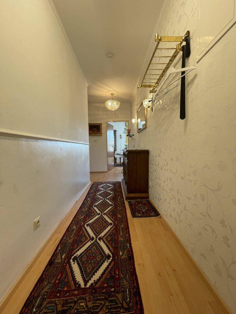 Langer Flur mit Holzboden, Teppichläufer und Garderobe an der Wand.