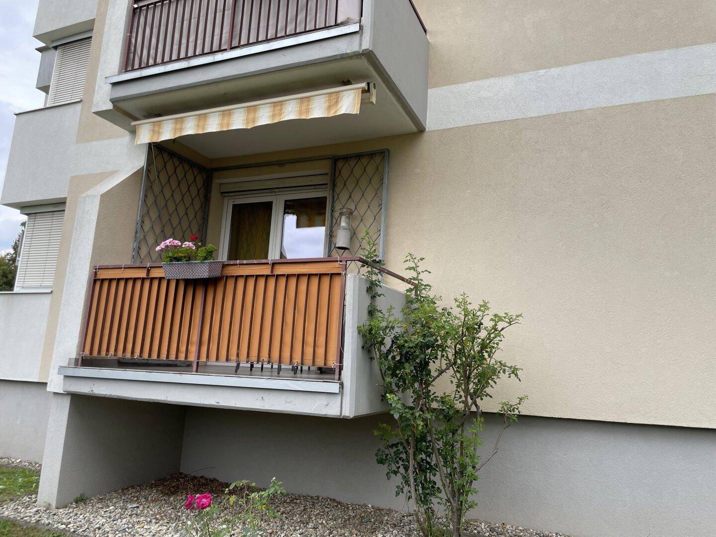 Kleiner Balkon mit Holzgeländer und Markise an der Fassade des Gebäudes.
