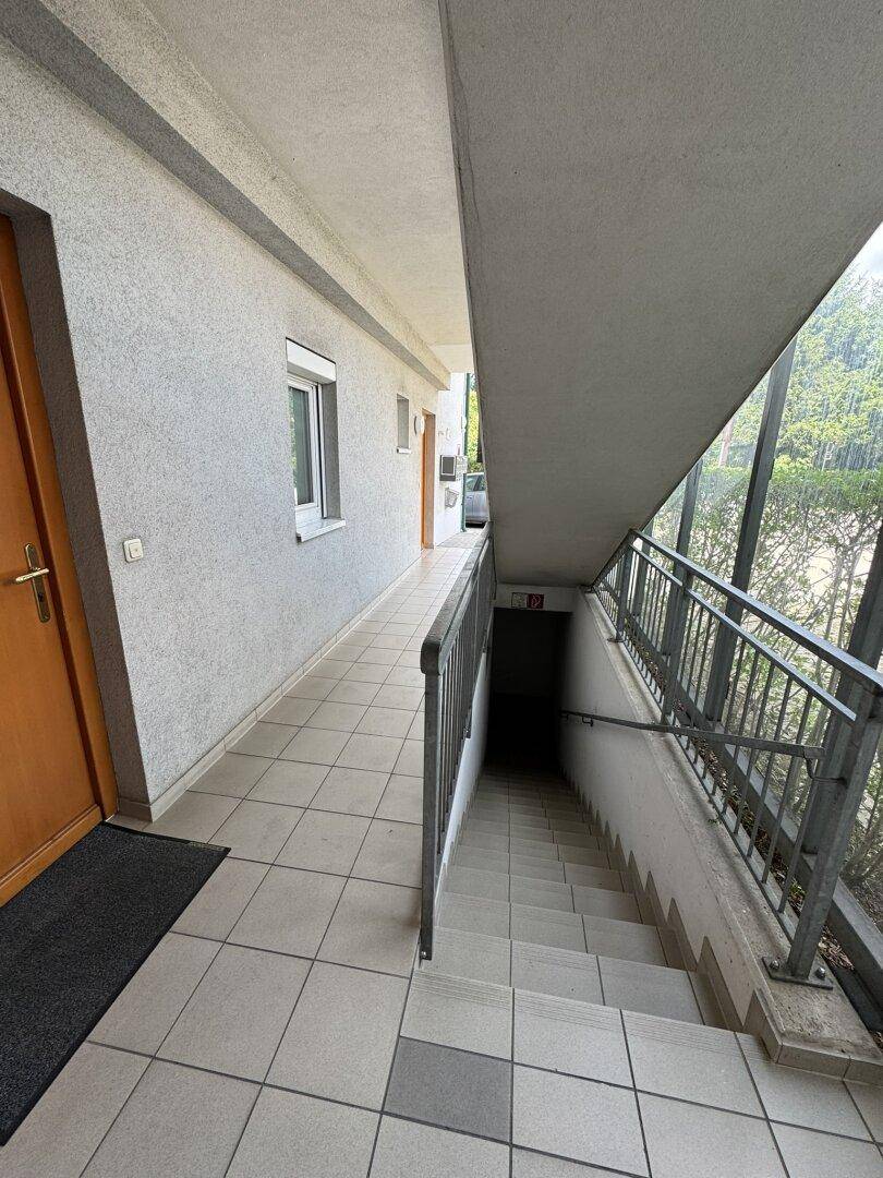 Außenflur mit Zugang zu Wohnungen und Treppe zum Untergeschoss, ausgestattet mit Fliesenboden.
