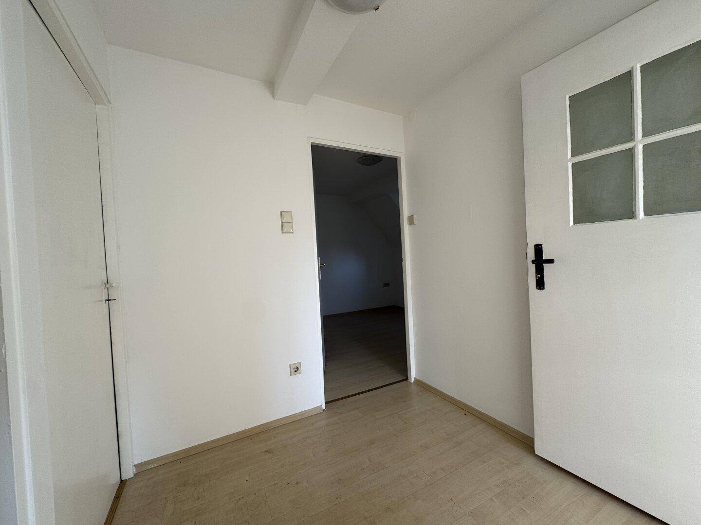 Kleiner Flur mit Laminatboden und weißen Türen, der zu weiteren Räumen führt.