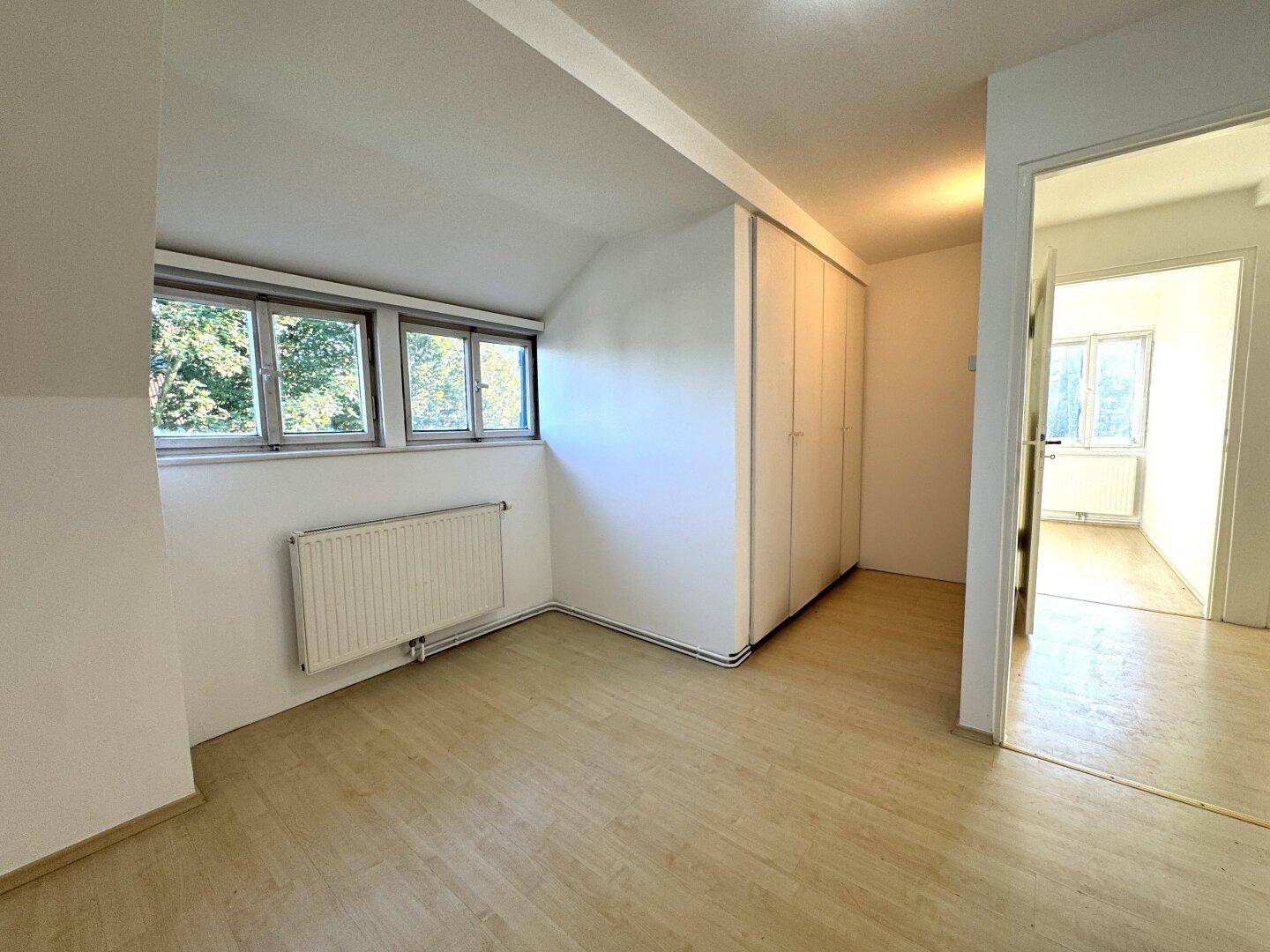 Geräumiges Schlafzimmer im Dachgeschoss mit Einbauschränken, Laminatboden und Fenstern.