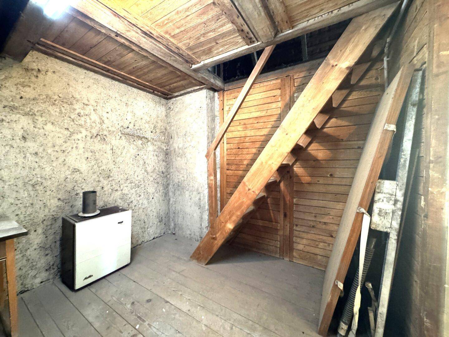 Geräumiger Dachboden mit Holzboden, schrägen Wänden und sichtbaren Holzstrukturen.