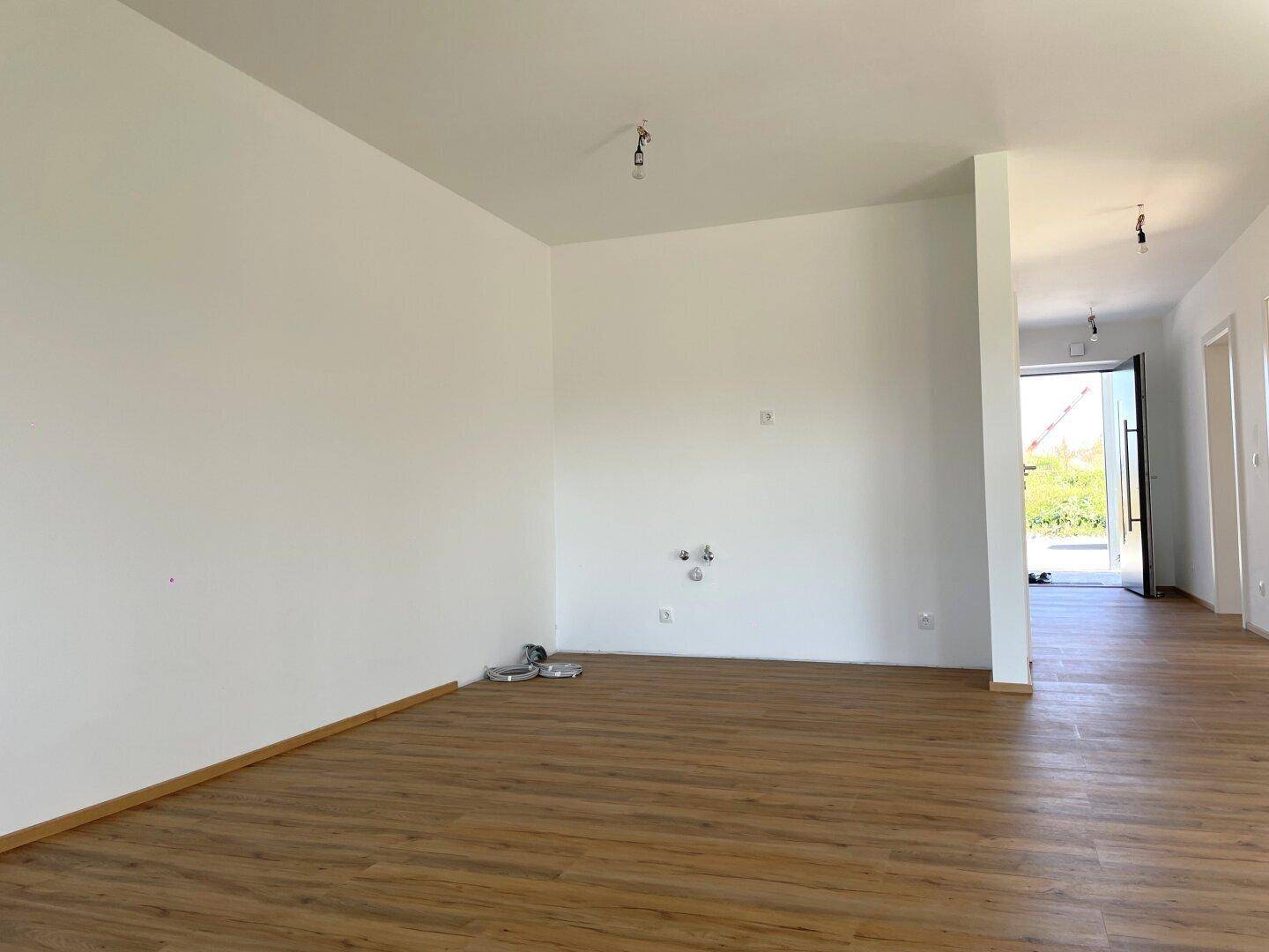 Heller Wohnbereich mit Laminatboden und Anschlüssen für eine offene Küche, bereit zur Gestaltung.