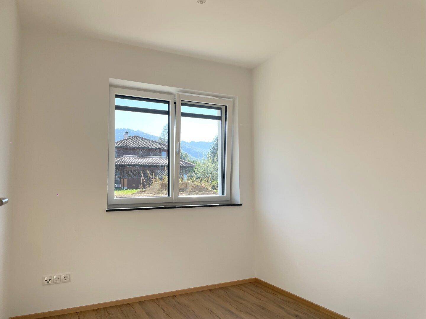 Helles Zimmer mit Laminatboden und Fenster, das einen weiten Blick auf die Landschaft ermöglicht.