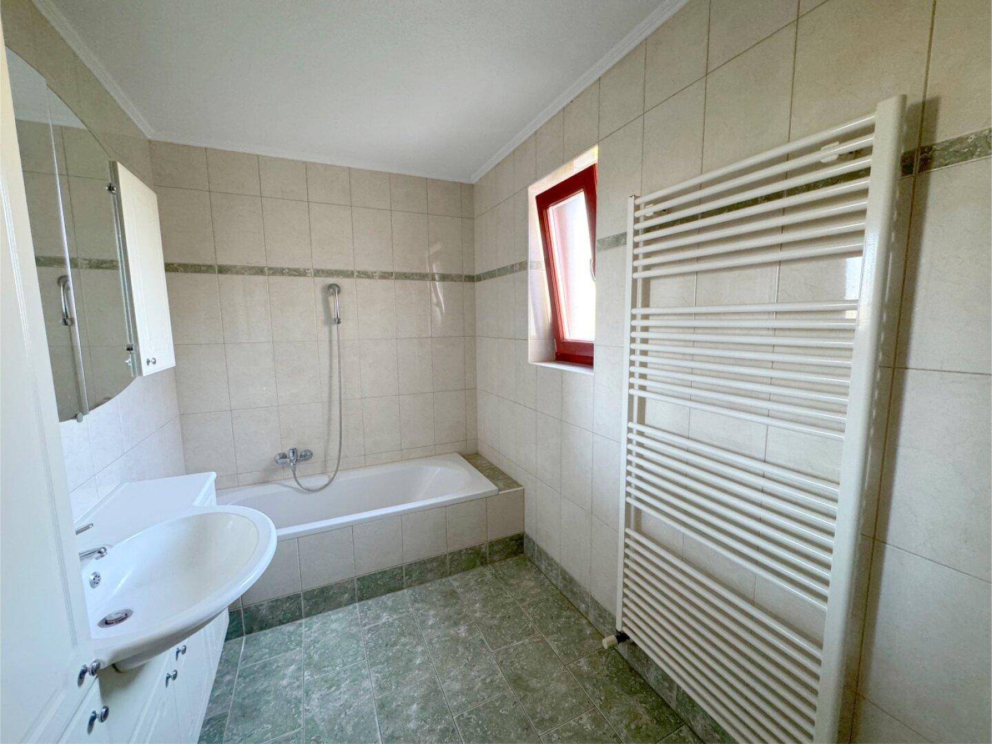 Badezimmer mit Badewanne, Dusche, Waschbecken und einem beheizten Handtuchhalter.