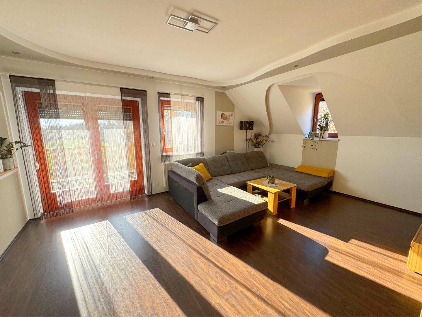 Helles Wohnzimmer mit Balkonzugang, großen Fenstern und viel Tageslicht.