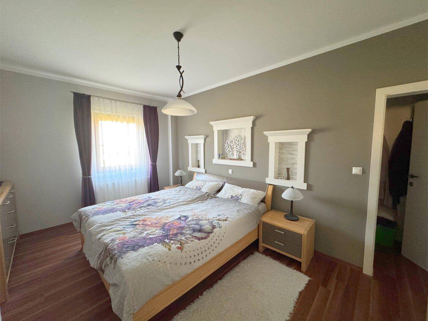 Helles Schlafzimmer mit Doppelbett, Holzboden und moderner Dekoration.