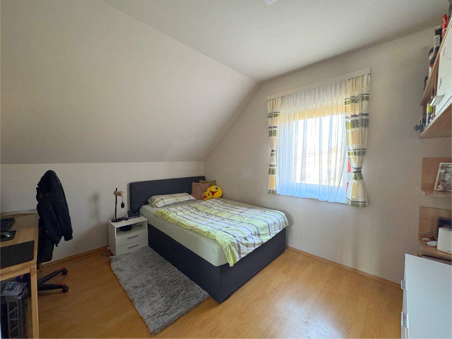 Schlafzimmer im Dachgeschoss mit Einzelbett, Laminatboden und Dachschräge.
