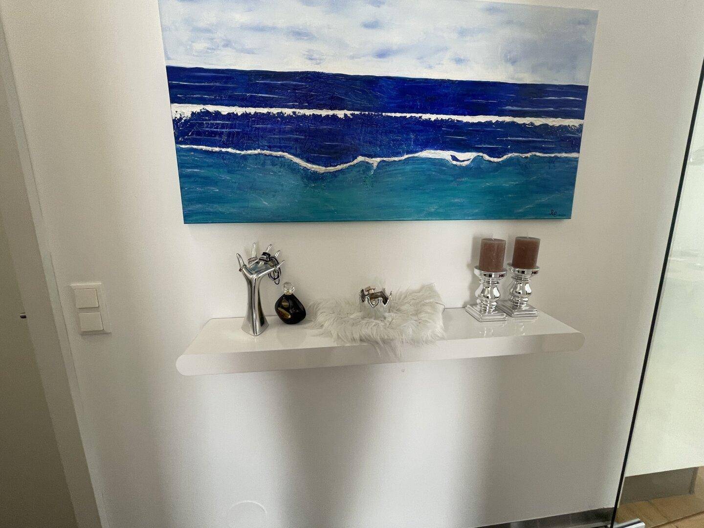 Dekorative Ablage im Flur mit Kunstwerk und stilvollen Accessoires an der Wand.