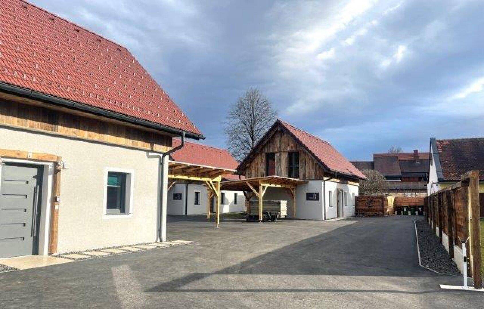 Mehrere moderne Häuser mit Carports und gepflasterten Zufahrten, eingebettet in eine ländliche Umgebung.
