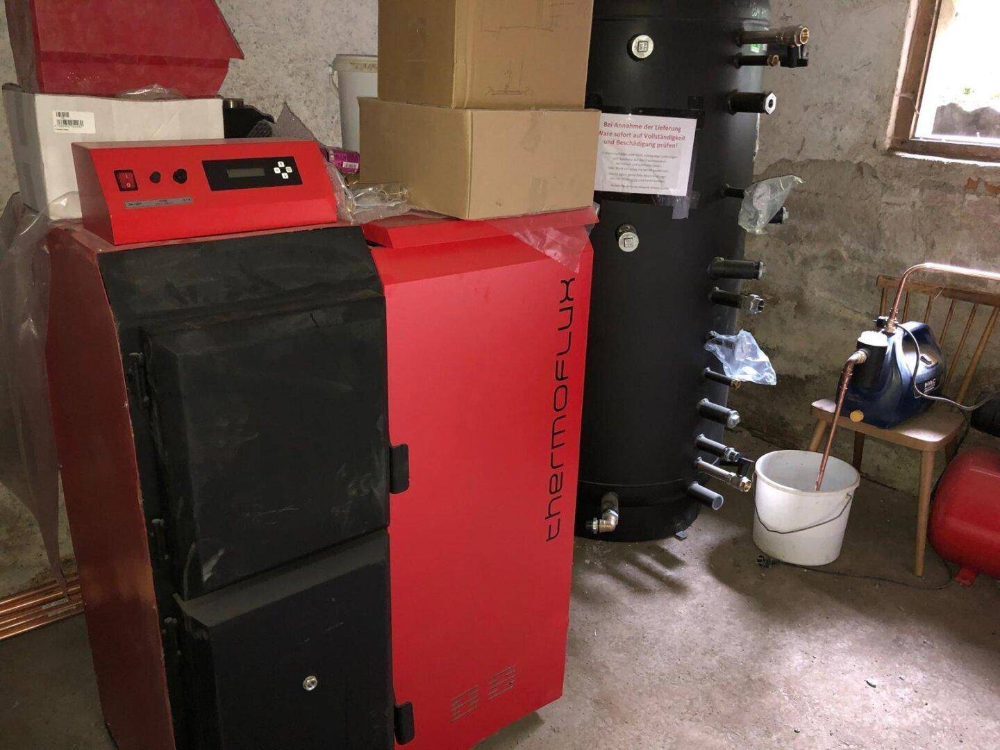 Heizraum mit modernem Pelletkessel und großem Warmwasserspeicher für effiziente Wärmeversorgung.