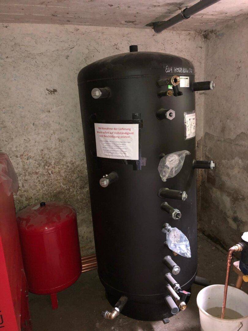Großer schwarzer Warmwasserspeicher im Heizraum, bereit für die Installation des Heizsystems.