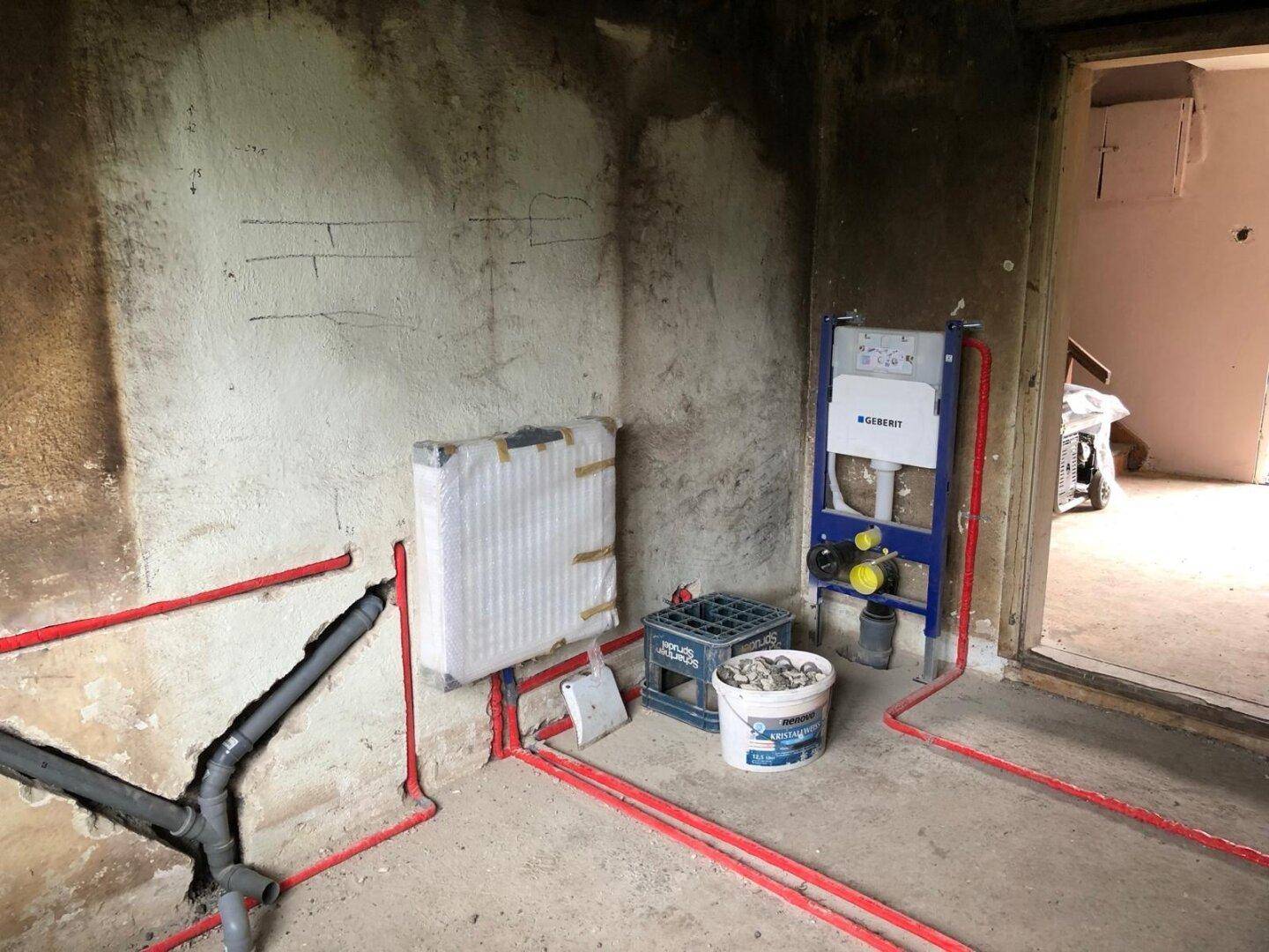 Rohbau eines Badezimmers mit sichtbaren Wasserleitungen und Vorinstallation für Wand-WC.