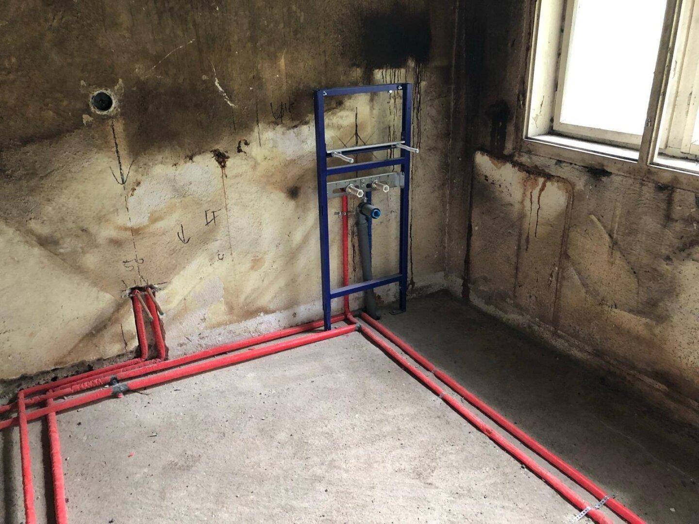 Vorinstallation für ein Wand-WC und Heizungsrohre in einem Raum, der renoviert wird.